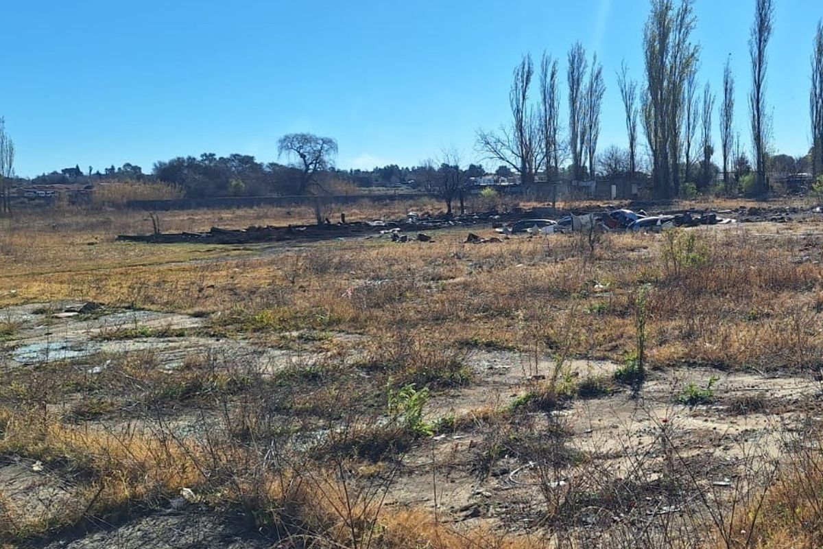 An expansive, undeveloped plot of land featuring dry vegetation and a concrete slab foundation, suitable for future development or agricultural use.