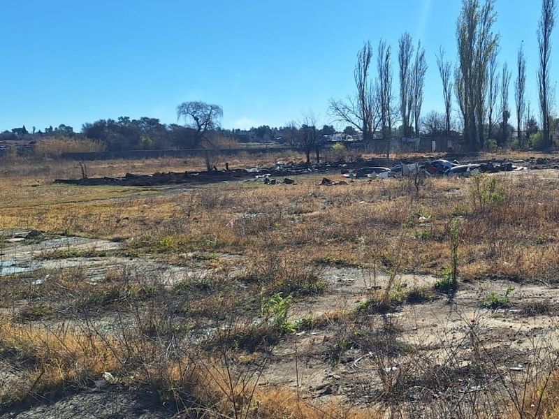 An expansive, undeveloped plot of land featuring dry vegetation and a concrete slab foundation, suitable for future development or agricultural use.