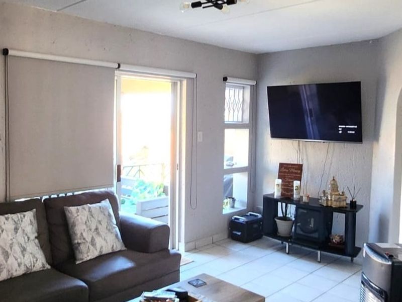 A living room featuring tiled flooring, a sliding glass door leading to an outdoor area, and roller blinds.