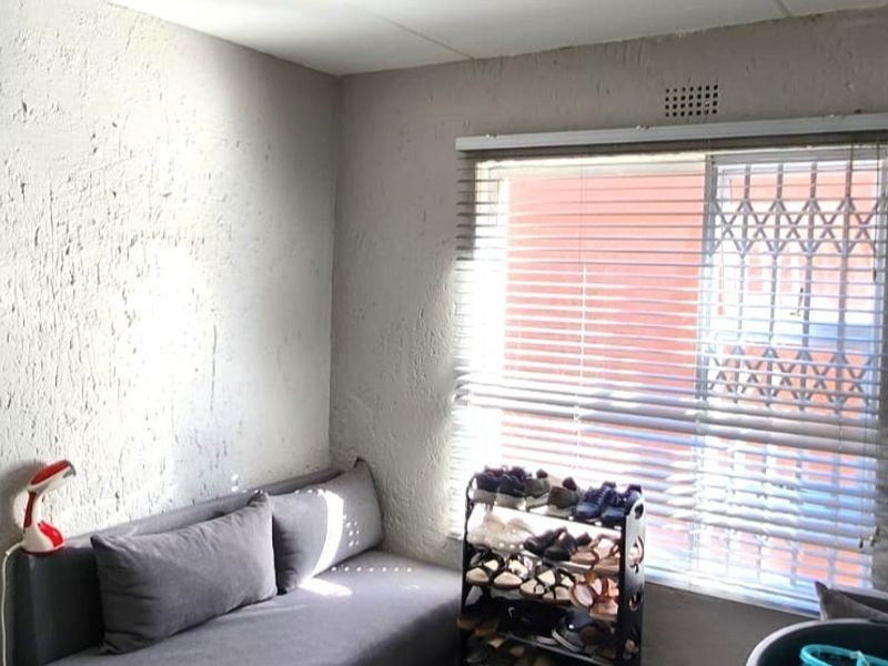 A bedroom featuring textured walls, a window with venetian blinds, and an integrated security gate.
