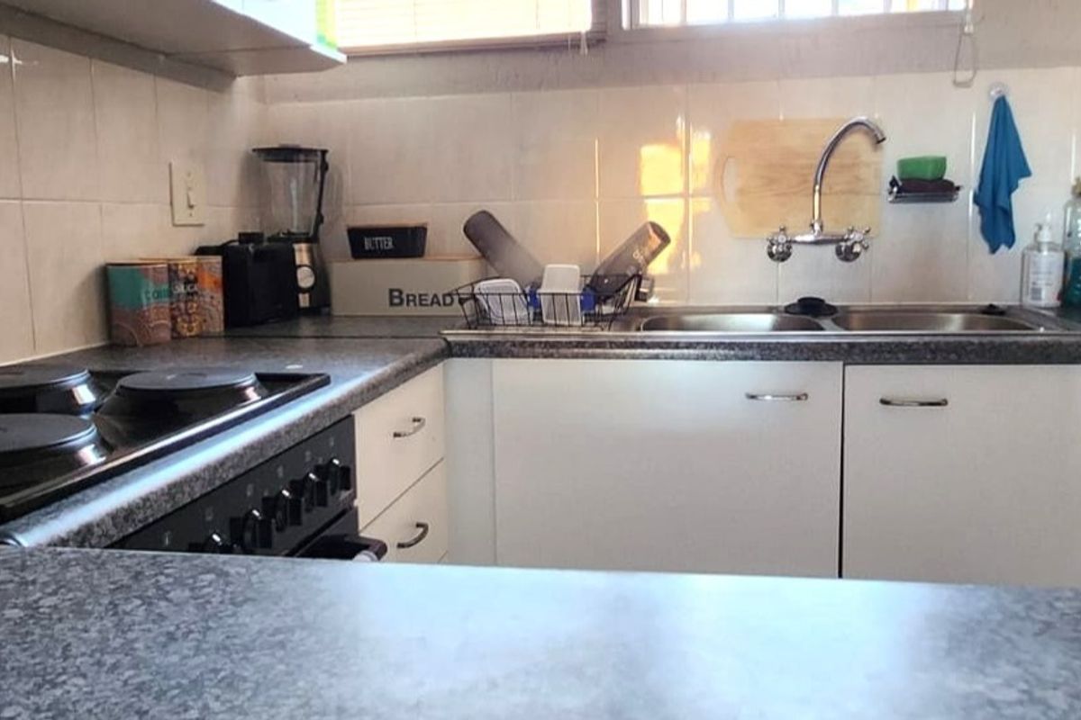 A functional kitchen featuring built-in cabinetry, laminate countertops, a double basin sink, and a built-in electric oven and hob.