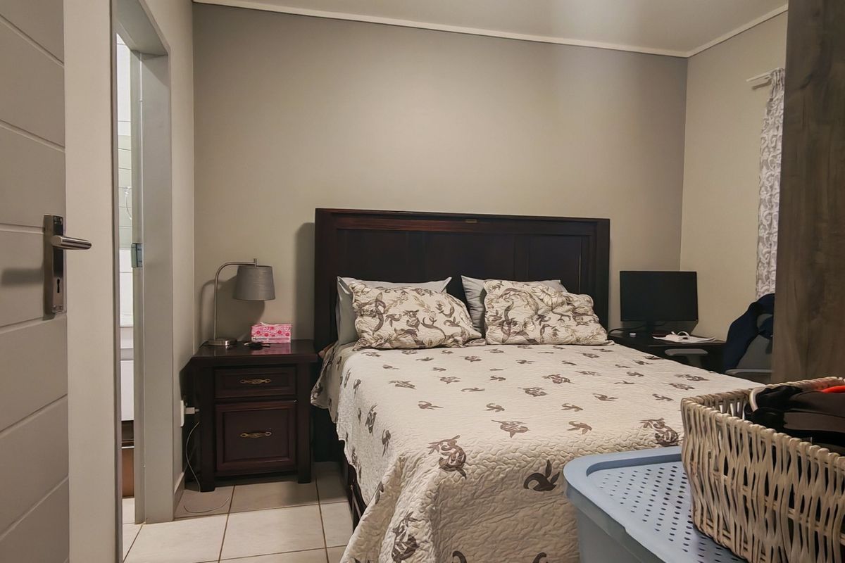 A functional bedroom featuring tiled flooring and direct access to an en-suite bathroom, providing a practical layout for comfortable living.