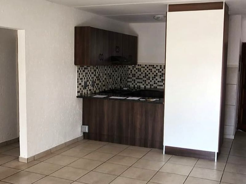 Open plan living area featuring a kitchen with built-in cabinetry, mosaic tile backsplash, and ceramic floor tiles throughout.