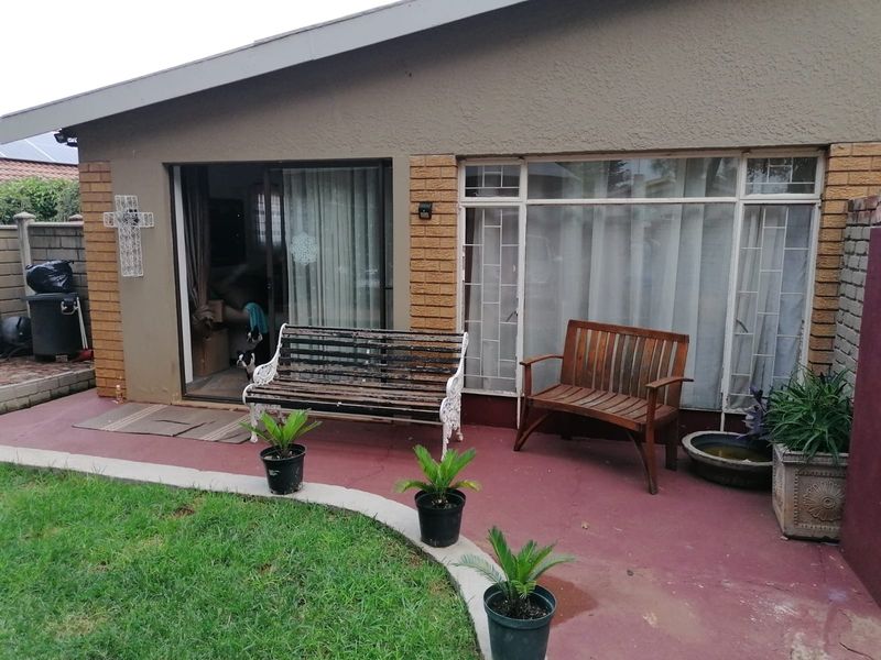 A paved patio area featuring a sliding door entrance and large windows, providing direct access to the garden space.
