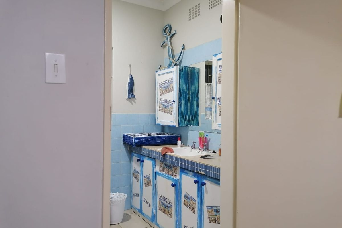 A bathroom featuring a vanity cabinet with a tiled countertop and integrated sink, finished with blue wall tiles and neutral floor tiles.