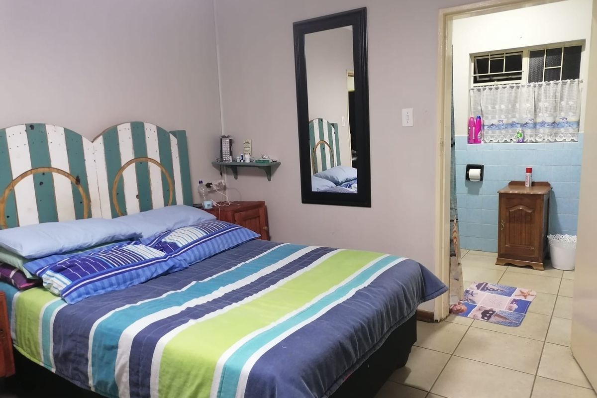 A bedroom featuring tiled flooring and direct access to an en-suite bathroom with wall tiling and a window.