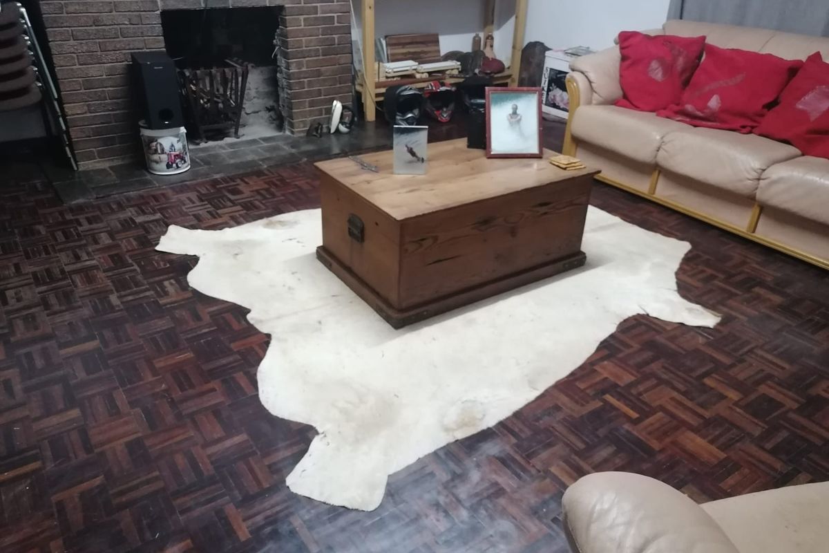 A living room featuring a traditional brick fireplace and classic parquet flooring, offering a cozy foundation for potential interior updates.