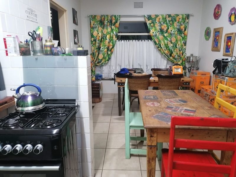Open plan kitchen and dining area featuring tiled flooring, a gas stove, and a tiled splashback, offering a functional layout for daily living.