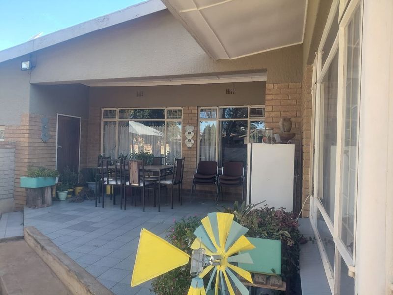 A covered outdoor patio area featuring tiled flooring and brick wall accents, providing a functional space for outdoor dining and relaxation.