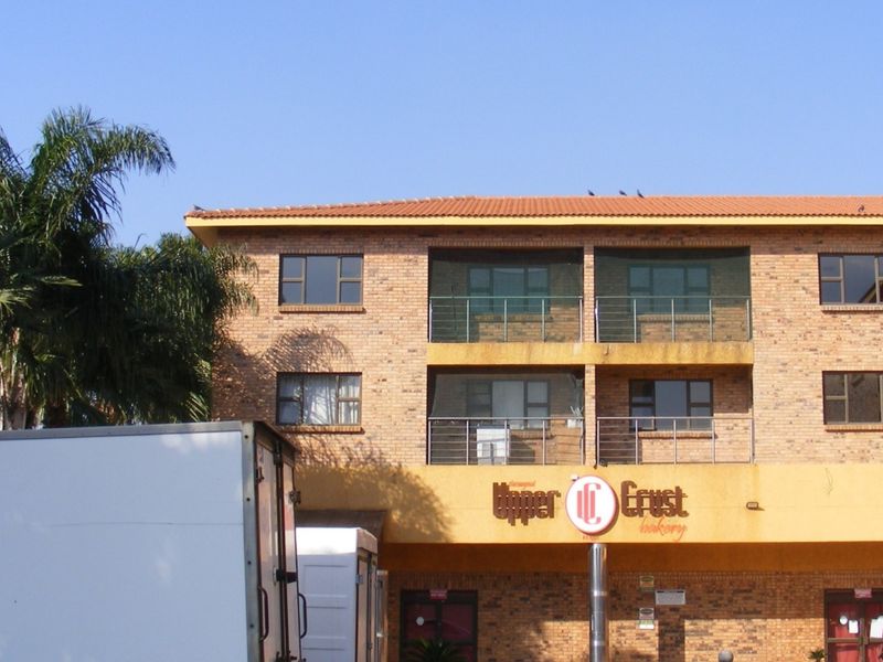 Front elevation of a multi-story apartment building featuring face brick construction, tiled roofing, and private balconies with metal balustrades.