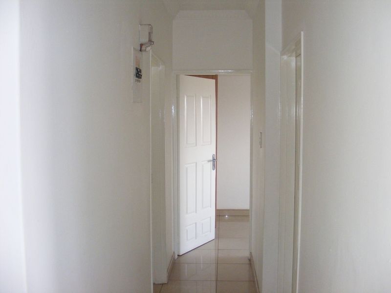 A clean and simple interior hallway featuring tiled flooring and access to adjacent rooms through standard internal doors.