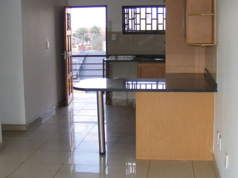 Open plan kitchen area featuring granite countertops, built-in cabinetry, and a breakfast bar, leading out to a balcony with security gate.