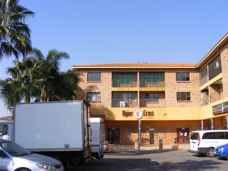 Front elevation of a multi-story apartment building featuring face brick construction, balconies with metal railings, and ground-floor commercial space.