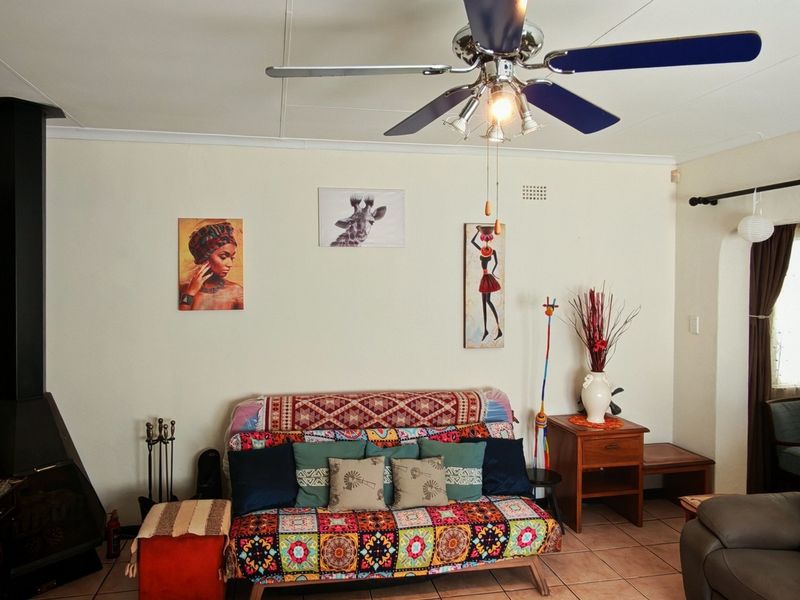 A living room featuring a freestanding fireplace, ceiling fan, and tiled flooring, with an arched doorway leading to an adjacent space.