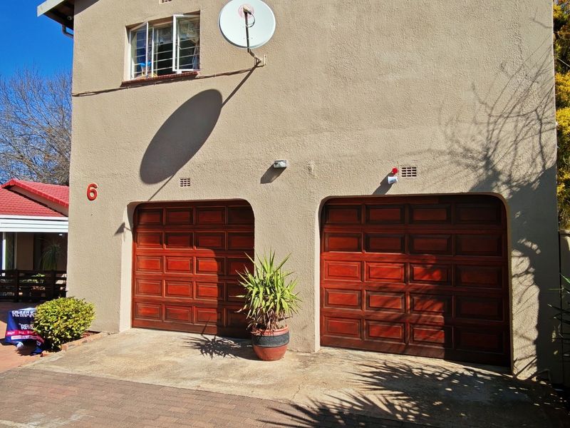 Front view of a residential property featuring a double garage with wooden doors and a paved driveway.