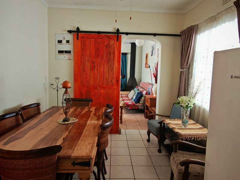 Dining area featuring ceramic floor tiles, a distinctive red sliding barn door, and an arched transition leading into the adjacent living space.