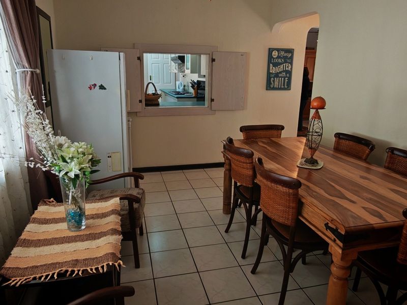 Dining room featuring tiled flooring and a convenient serving hatch connecting to the kitchen area through an arched doorway.