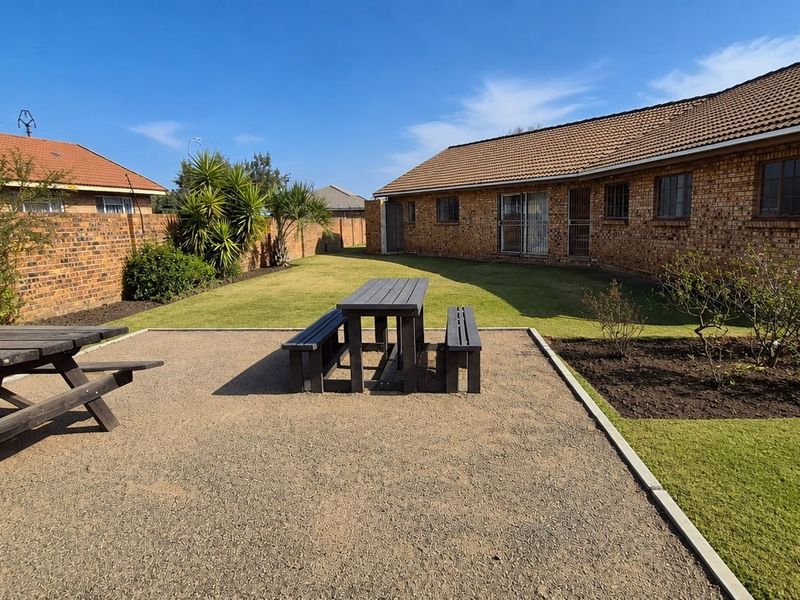A spacious rear garden featuring a gravel patio area, well-maintained lawn, and brick boundary walls, providing a private outdoor space.