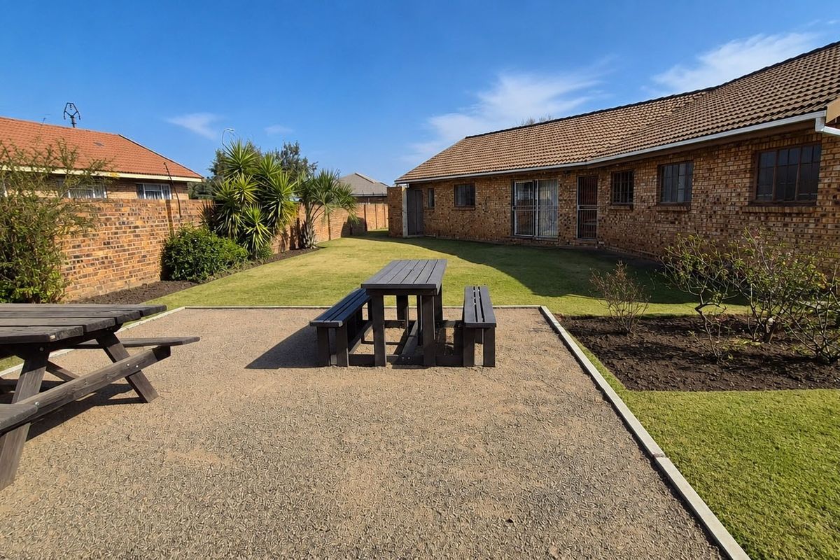 A spacious rear garden featuring a gravel patio area, well-maintained lawn, and brick boundary walls, providing a private outdoor space.
