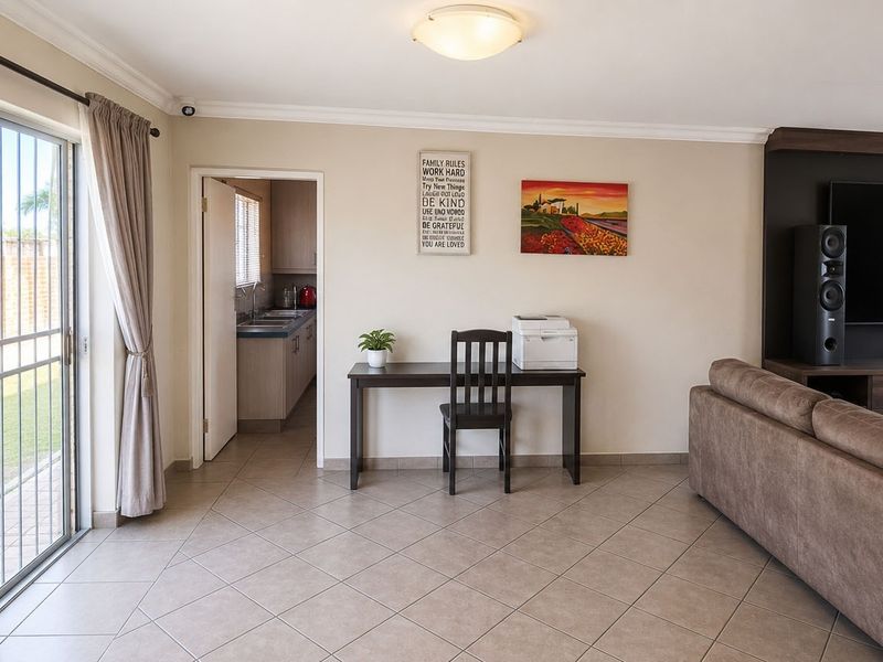 Open-plan living area featuring tiled flooring, a built-in media unit, and a sliding glass door providing access to the exterior.