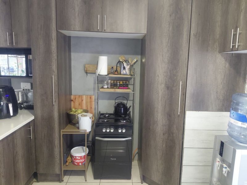 A functional kitchen featuring dark wood-grain cabinetry, tiled flooring, and a built-in gas stove with oven.