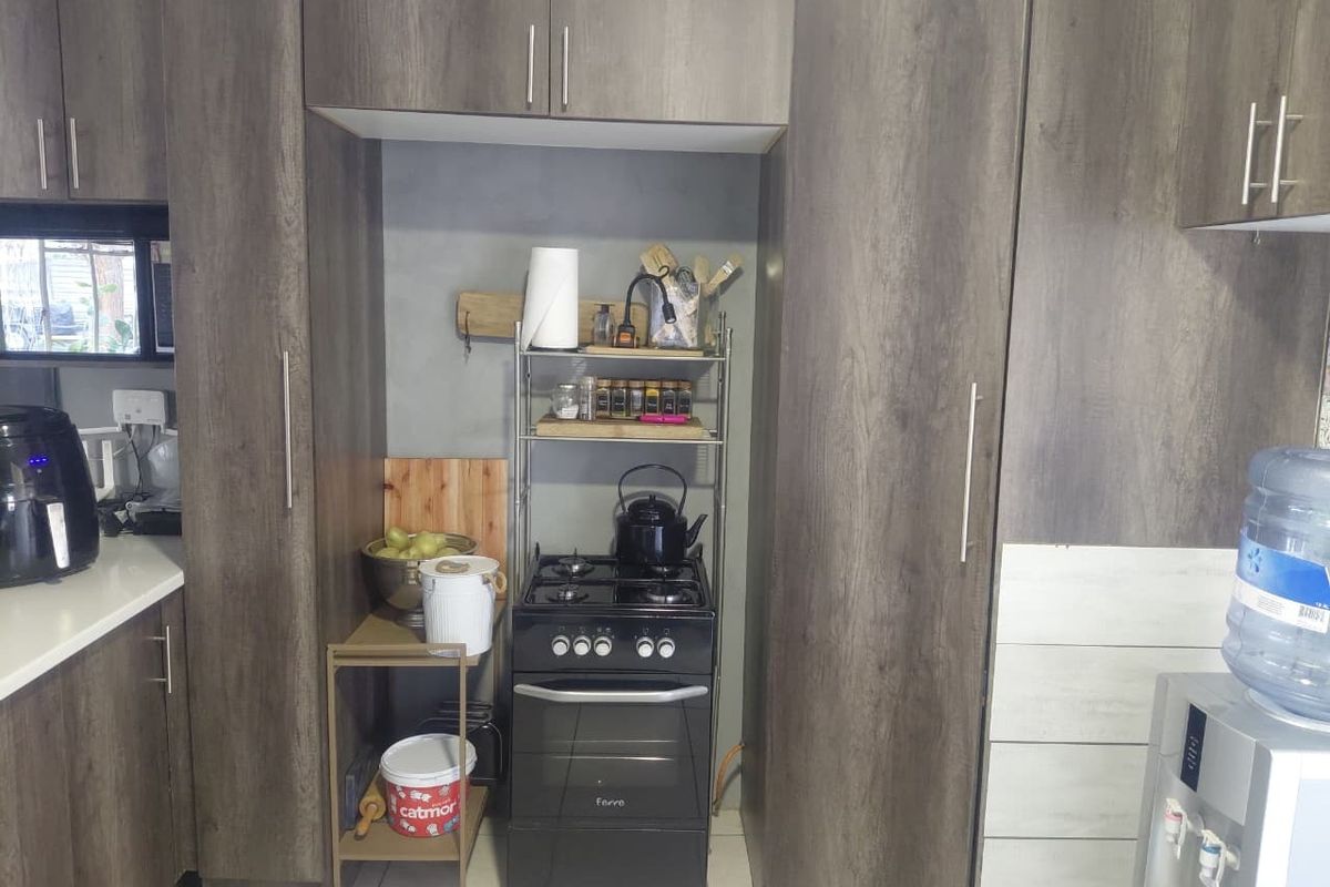 A functional kitchen featuring dark wood-grain cabinetry, tiled flooring, and a built-in gas stove with oven.