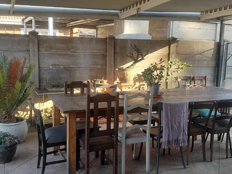 A covered outdoor patio area featuring concrete paving and a precast boundary wall, providing a functional space for outdoor dining and relaxation.