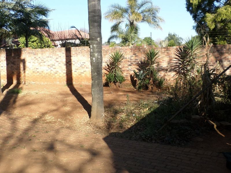 A spacious rear garden area featuring a brick boundary wall and paved section, offering significant potential for landscaping and outdoor improvement.