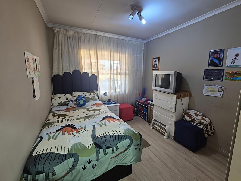 A standard bedroom featuring laminate flooring, neutral wall tones, and a ceiling-mounted spotlight fixture, providing a functional space for a bedroom.