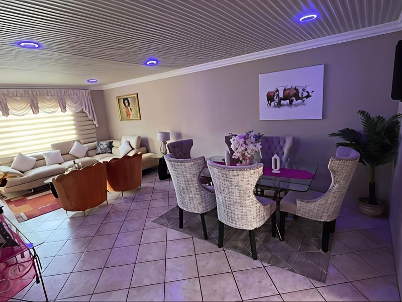 An open-plan living and dining area featuring tiled flooring, recessed ceiling lighting, and a coved ceiling design.