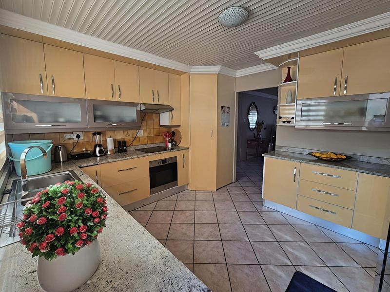 A functional kitchen featuring light-toned cabinetry, granite countertops, integrated appliances, and tiled flooring, offering a practical layout with ample storage space.