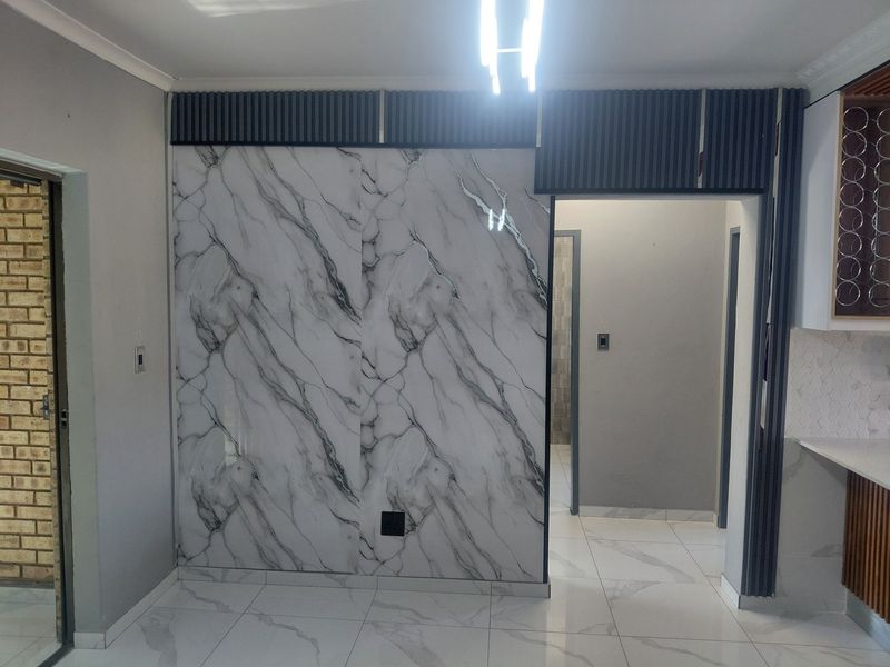 Modern open-plan living area featuring elegant marble-effect wall cladding, sleek porcelain floor tiles, and contemporary slatted timber accents with integrated wine storage.