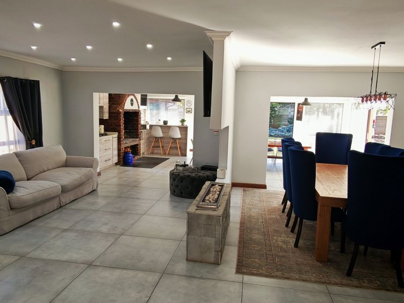 Spacious open-plan living and dining area featuring large format floor tiles, recessed lighting, and a cozy built-in fireplace with brick detailing.