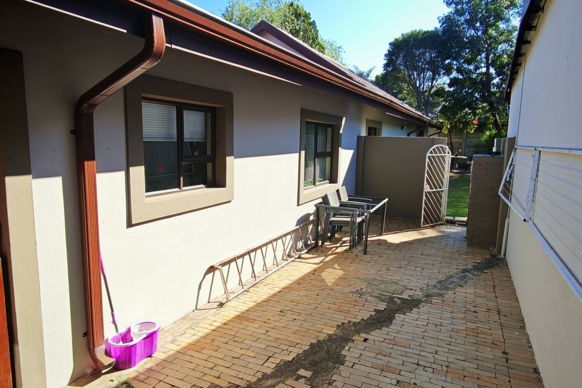 A rear exterior area featuring brick paving, a wall-mounted drying rack, and access to the garden through a security gate.