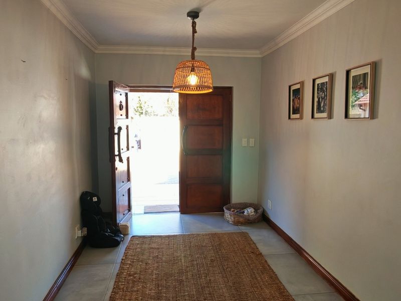 A welcoming entrance hall featuring tiled flooring, coving, and a solid timber front door, providing a bright and clean transition into the home.