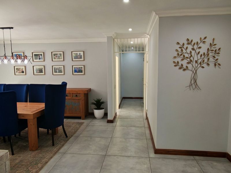 A well-maintained dining area featuring neutral walls, tiled flooring, recessed lighting, and a decorative security gate leading to the hallway.