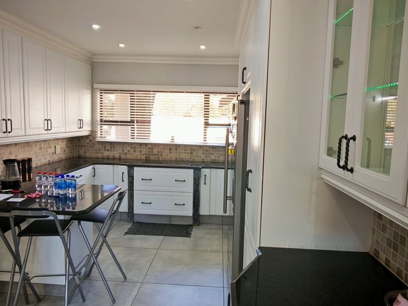 A well-maintained kitchen featuring white cabinetry, granite countertops, mosaic tile backsplash, and recessed lighting, offering a clean and functional workspace.