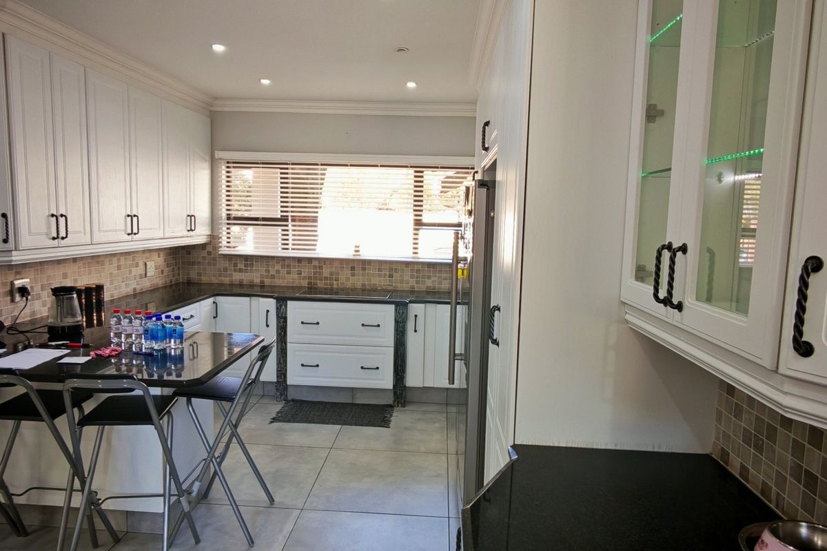 A well-maintained kitchen featuring white cabinetry, granite countertops, mosaic tile backsplash, and recessed lighting, offering a clean and functional workspace.