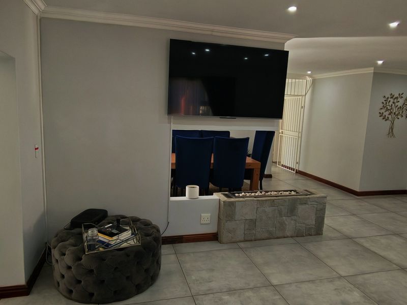 Spacious living area featuring tiled flooring, recessed lighting, and a central stone-clad fireplace, with direct access to an outdoor patio space.