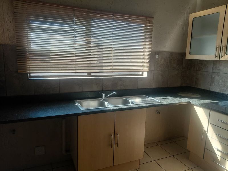 A functional kitchen featuring granite countertops, a double bowl sink, tiled backsplash, and built-in cabinetry with ample storage space.