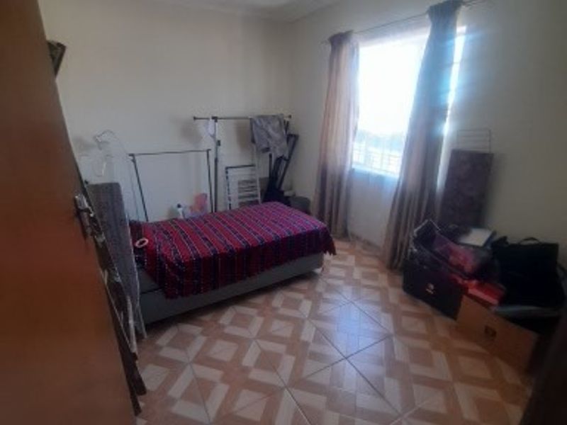A standard bedroom featuring tiled flooring and a ceiling fan, providing a functional space with natural light from the window.