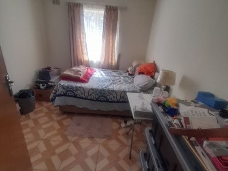 A standard bedroom featuring tiled flooring and recessed ceiling lighting, providing a functional space for rest.