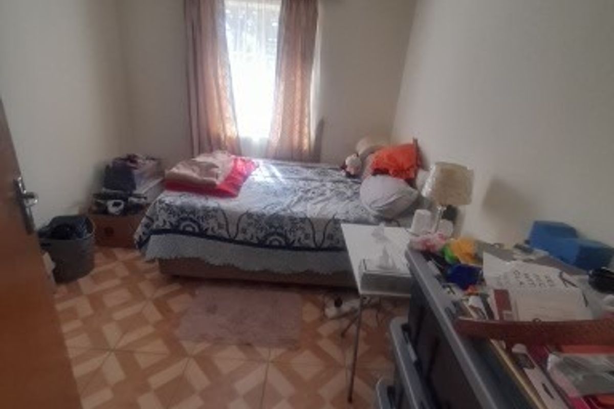 A standard bedroom featuring tiled flooring and recessed ceiling lighting, providing a functional space for rest.