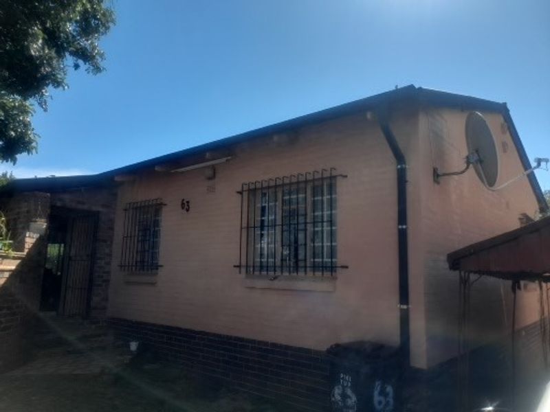 Front elevation of a single-story brick house featuring security bars on windows and a satellite dish installation.