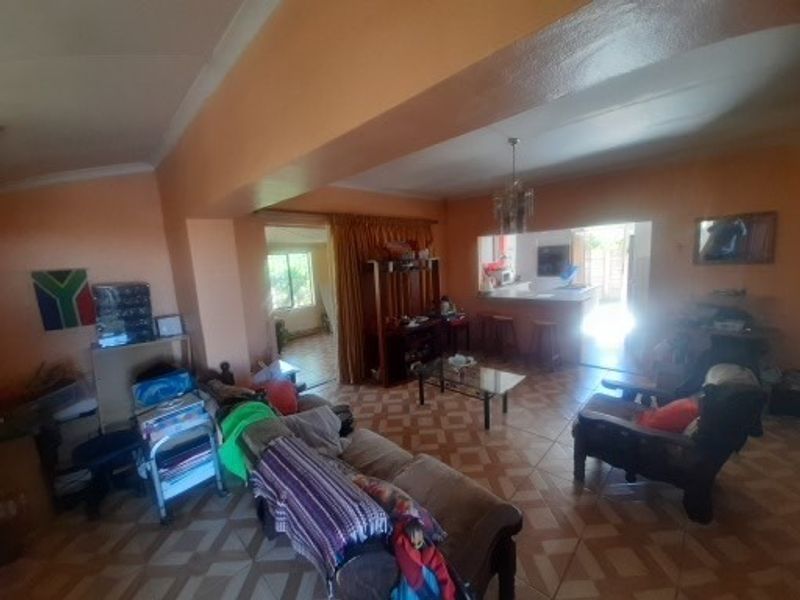 Open-plan living and kitchen area featuring tiled flooring and a breakfast bar, offering a functional layout with potential for modernization.