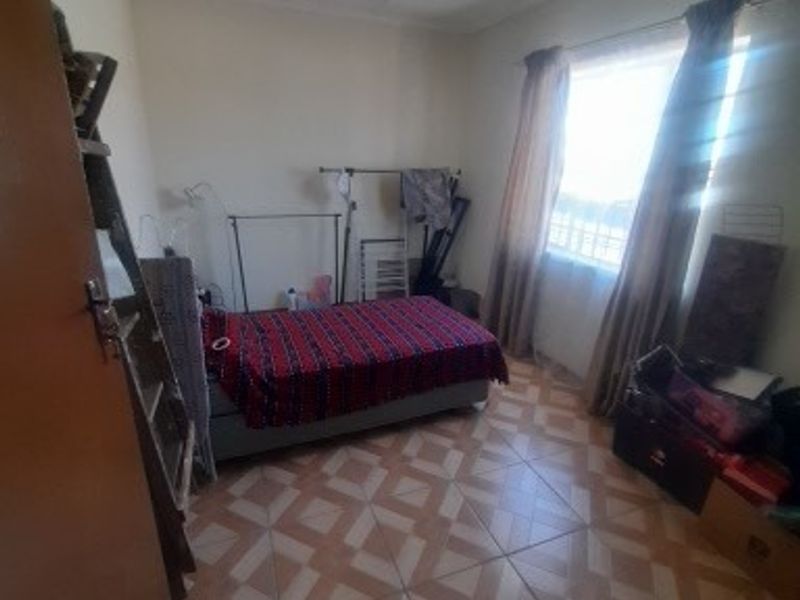 A bedroom featuring tiled flooring and a ceiling fan, offering a functional space ready for personalization.