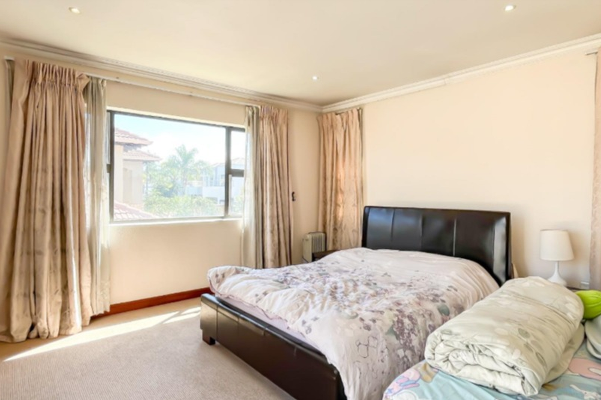 A spacious bedroom featuring neutral walls, carpeted flooring, recessed downlighting, and large windows that provide ample natural light.