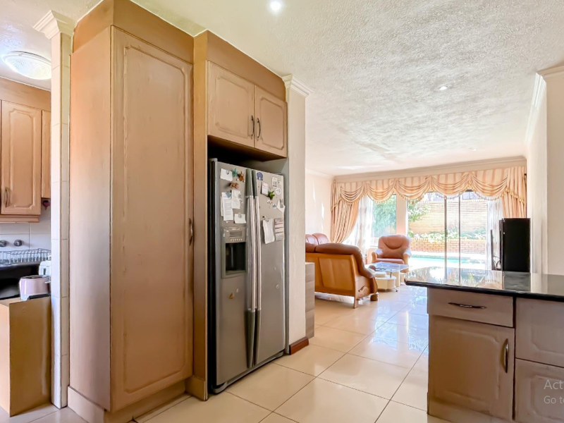 Open plan kitchen and living area featuring tiled floors, built-in cabinetry, and sliding glass doors leading to the outdoor pool area.