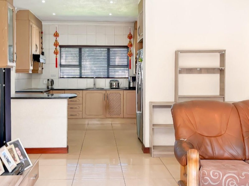 Open plan living area featuring a functional kitchen with built-in cabinetry, granite countertops, and tiled flooring throughout the space.