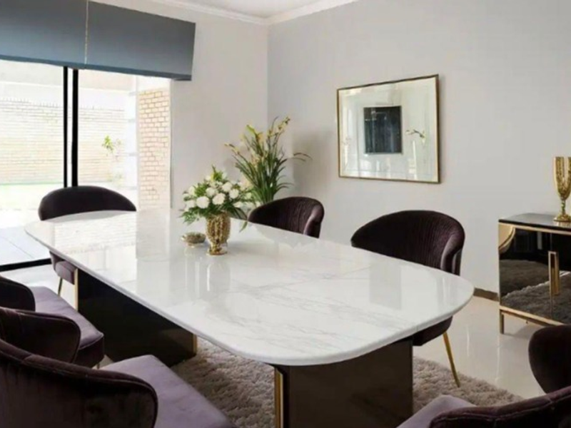 A well-maintained dining room featuring tiled flooring, cove molding, and a large sliding glass door providing access to the exterior.